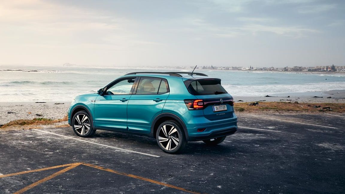 Син Volkswagen T-Cross, паркиран на паркинг до морския бряг при залез.