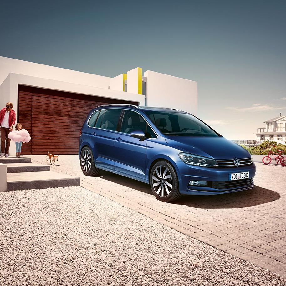 Син Volkswagen Touran паркиран пред модерен дом – перфектен семеен автомобил