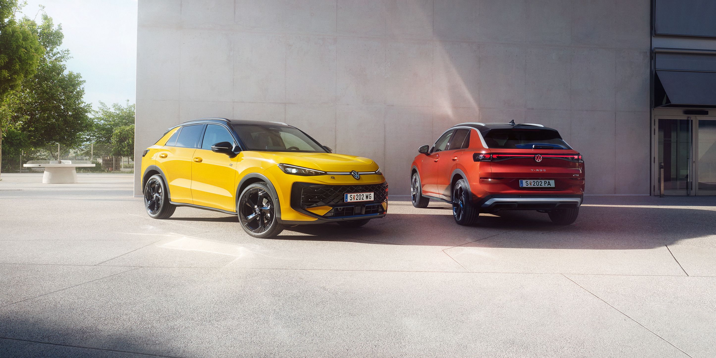 Жълт и червен Volkswagen T-Roc паркирани пред модерна сграда