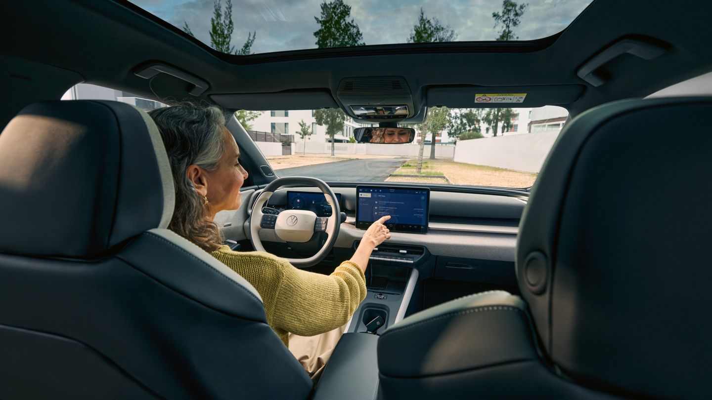Жена седи на шофьорското място на VW ID. Cross и управлява инфотейнмънт системата.