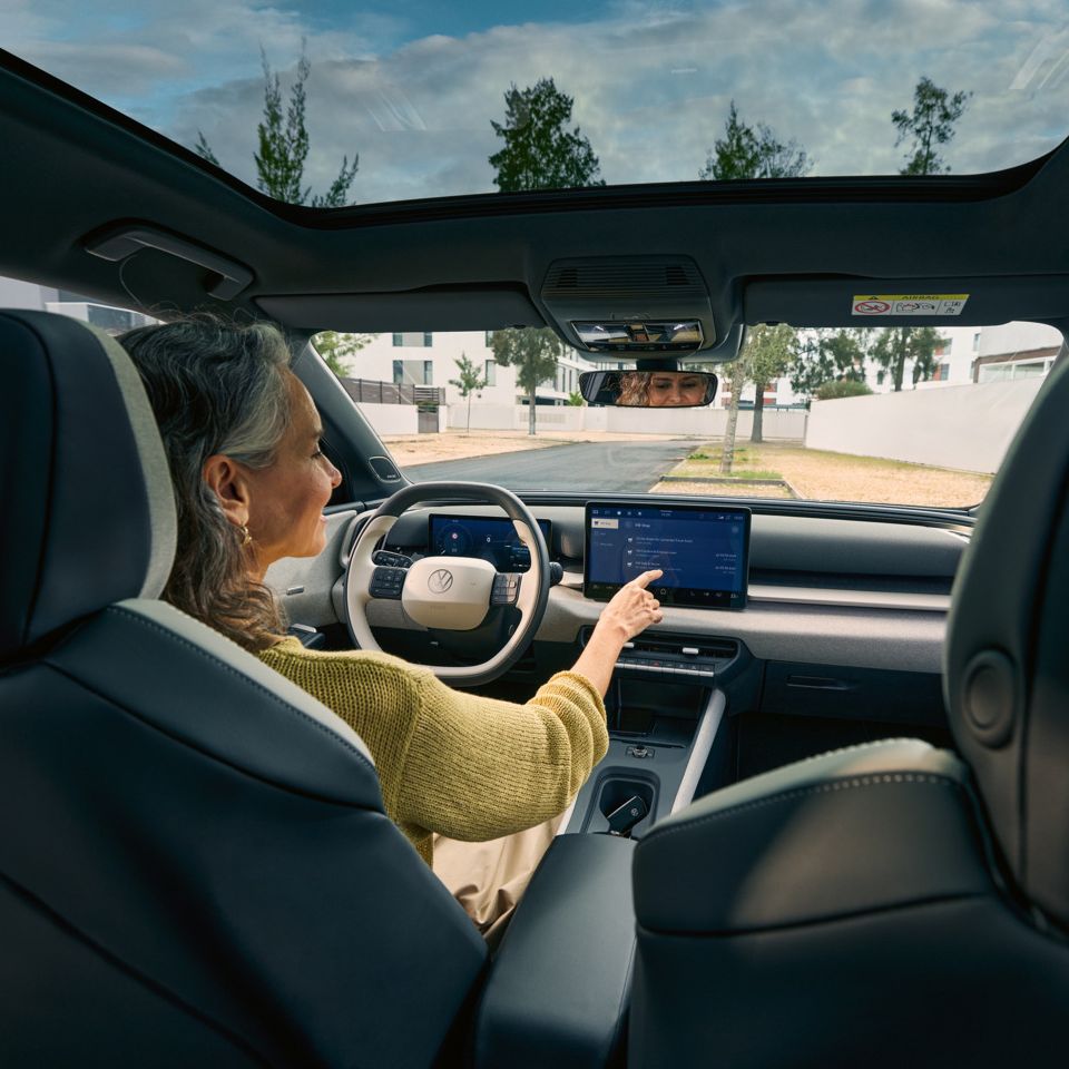 Жена седи на шофьорското място на VW ID. Cross и управлява инфотейнмънт системата.