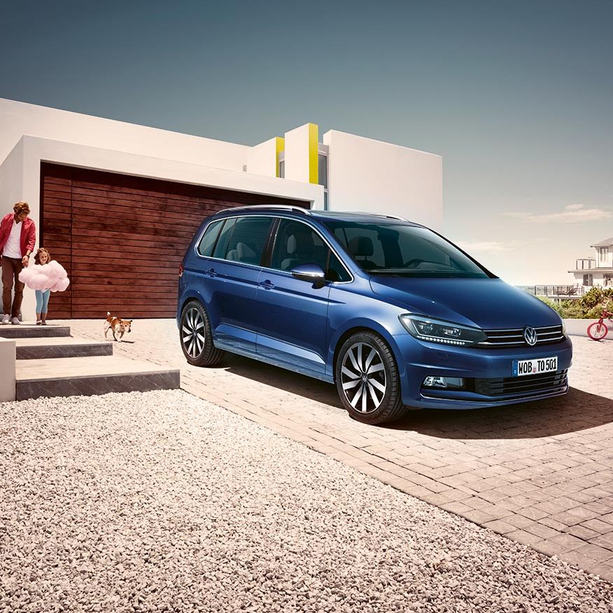 Син Volkswagen Touran паркиран пред модерен дом – перфектен семеен автомобил