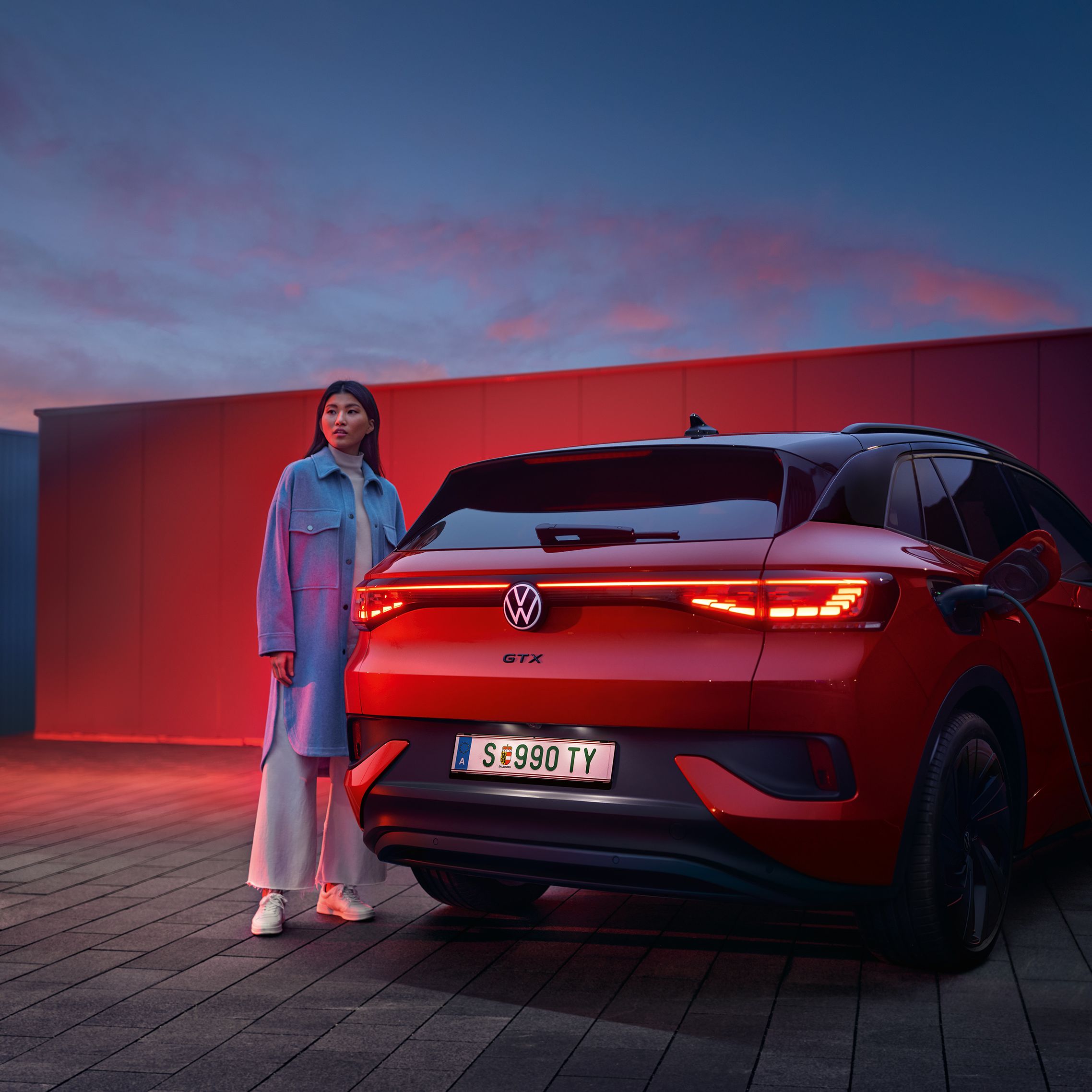 Изглед отзад на VW ID.4 GTX 4MOTION със стояща до него жена