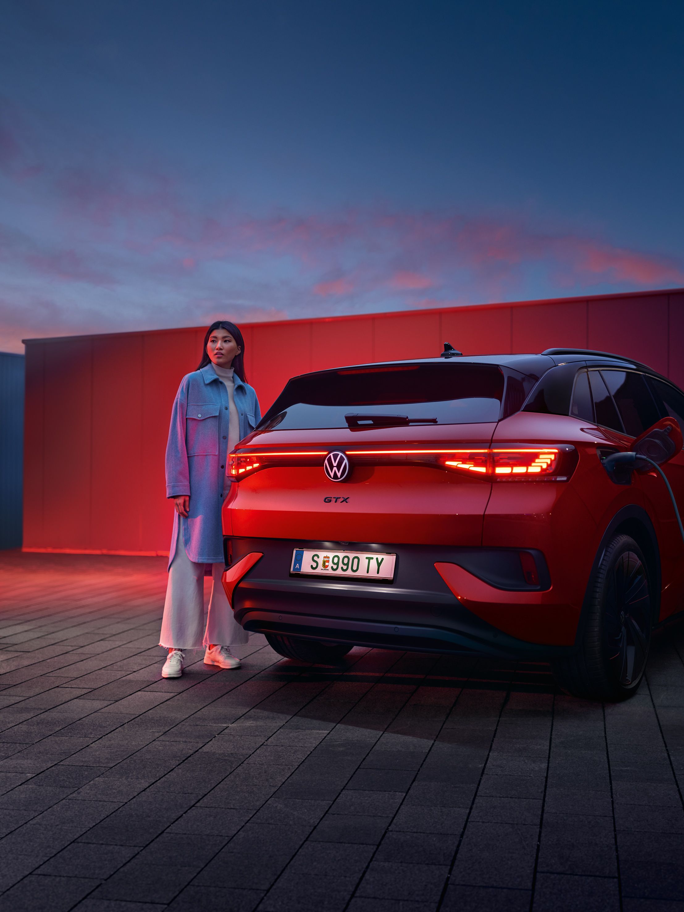 Изглед отзад на VW ID.4 GTX 4MOTION със стояща до него жена