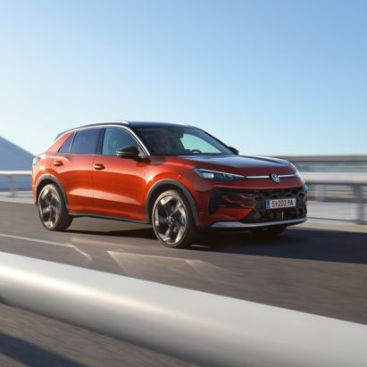 Червен Volkswagen T-Roc в движение по модерен мост.