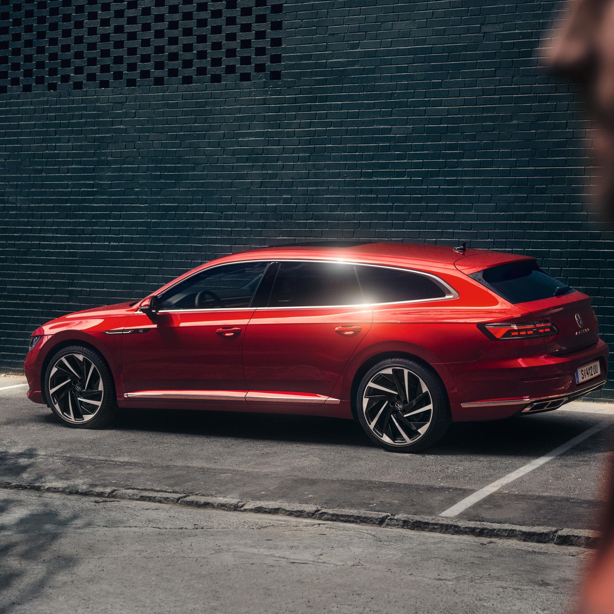 Стилен червен Volkswagen Arteon Shooting Brake паркиран до модерна тъмна стена