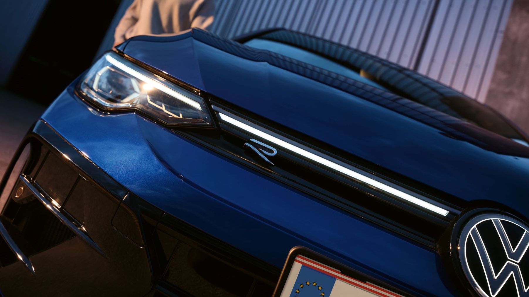 Golf R im Detailshot von der Vorderseite in schräger Ansicht mit Mann im Hintergrund.