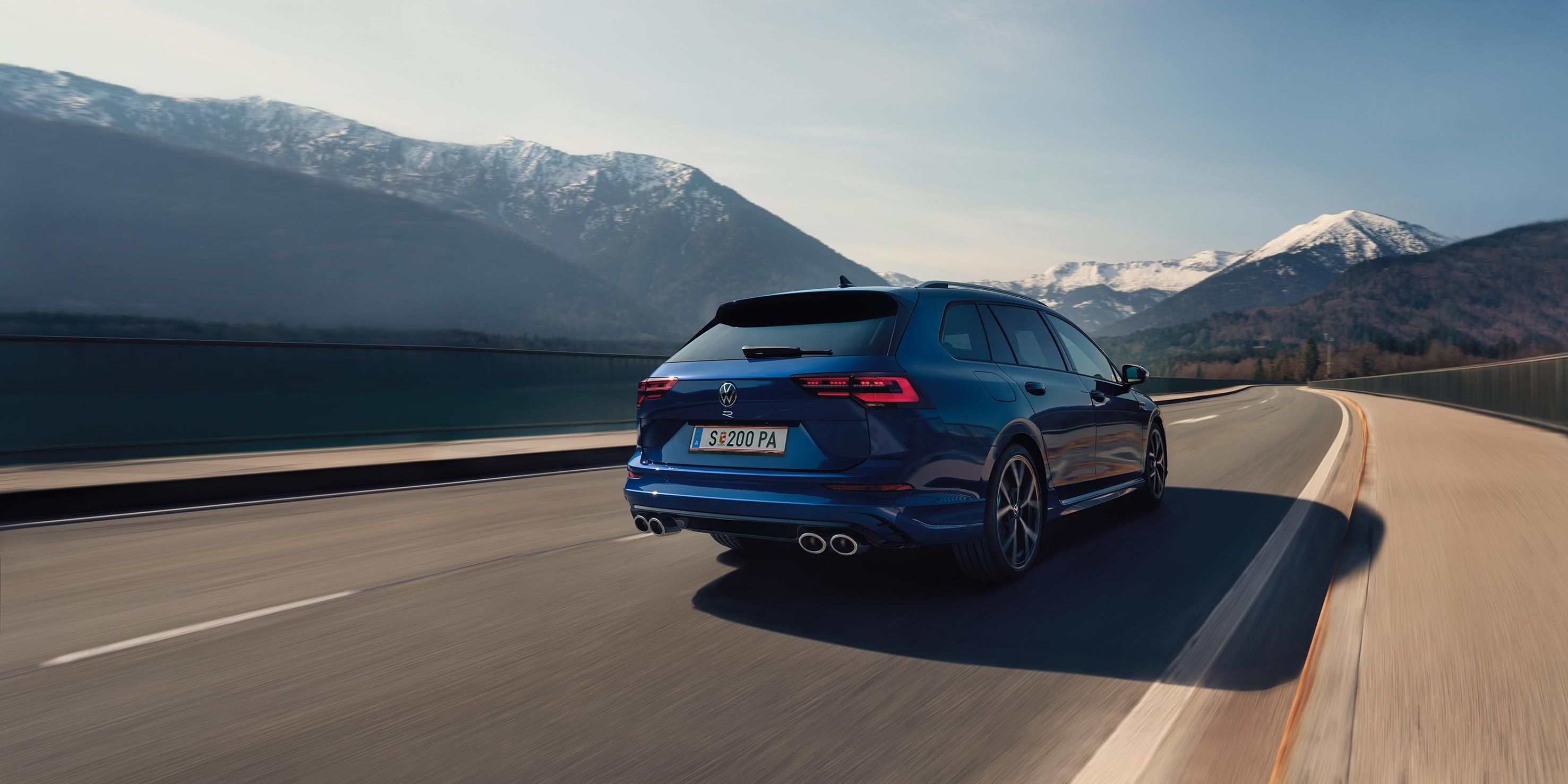 Задна част на син Volkswagen Golf Variant R в движение по планински път 