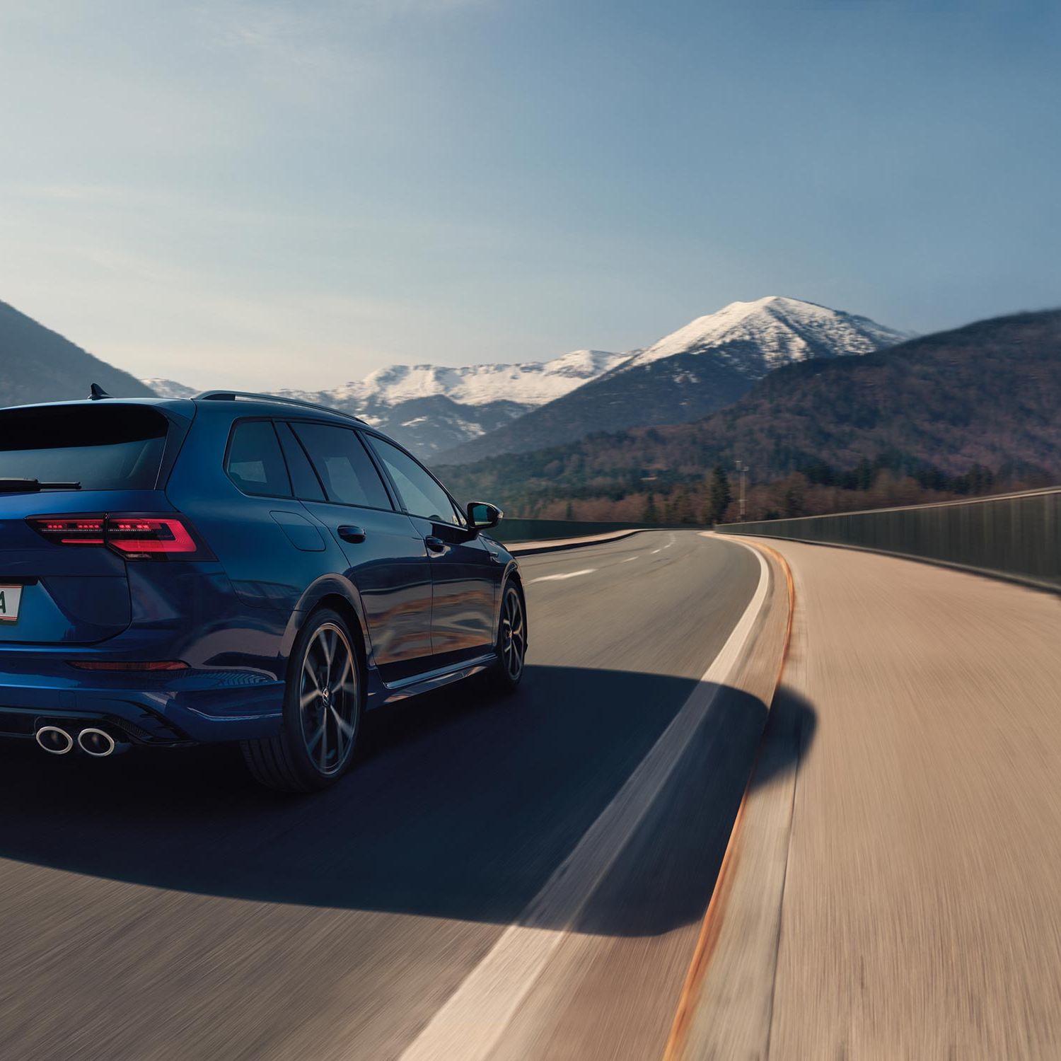 Задна част на син Volkswagen Golf Variant R в движение по планински път 