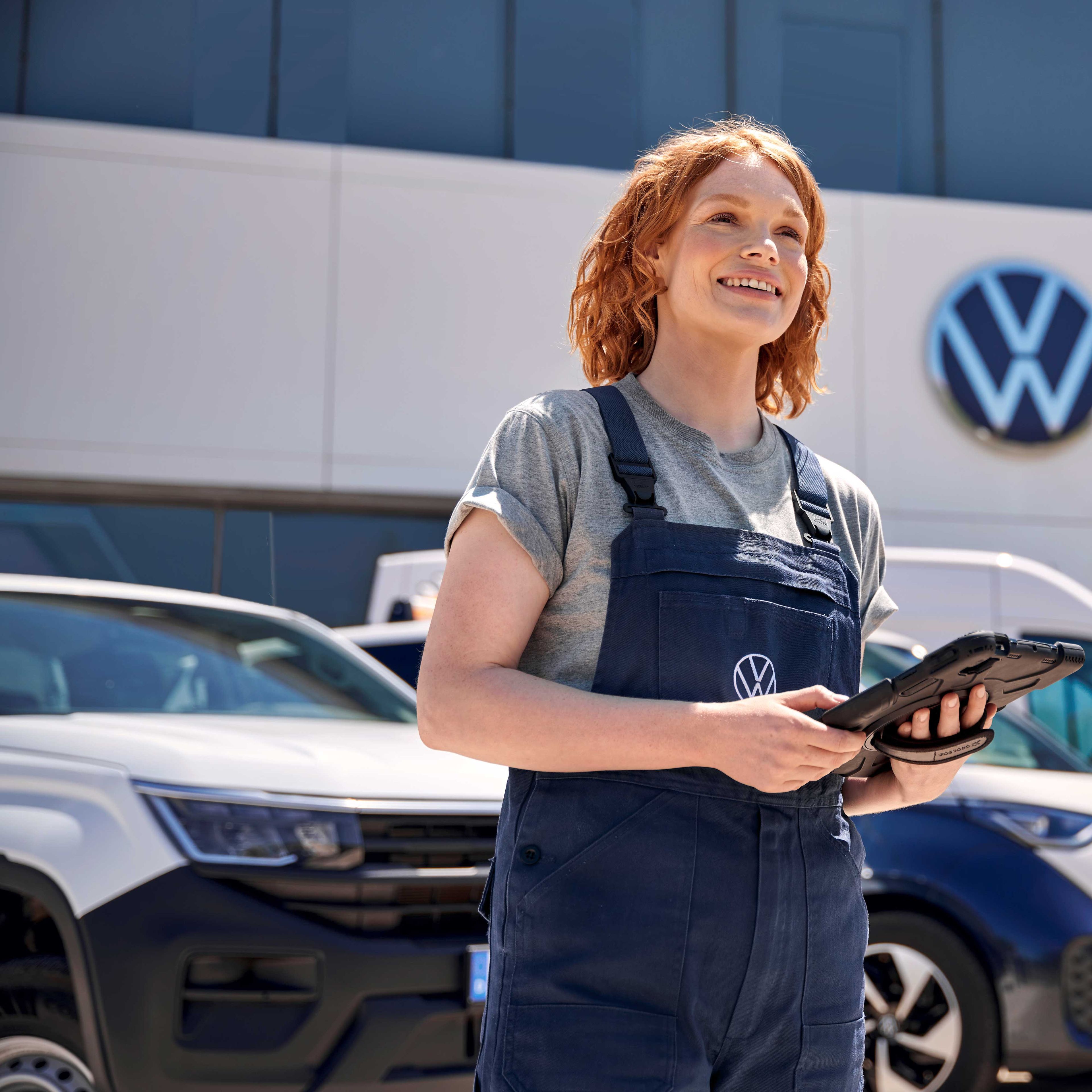 Eine Volkswagen Service Mitarbeiterin vor einem Volkswagen 