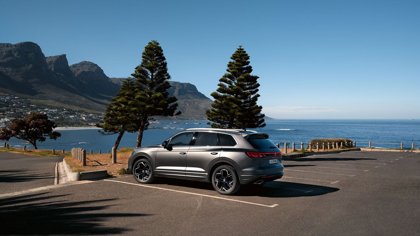 Паркиран на слънце VW Touareg Elegance, страничен изглед с морето и брега на заден план.