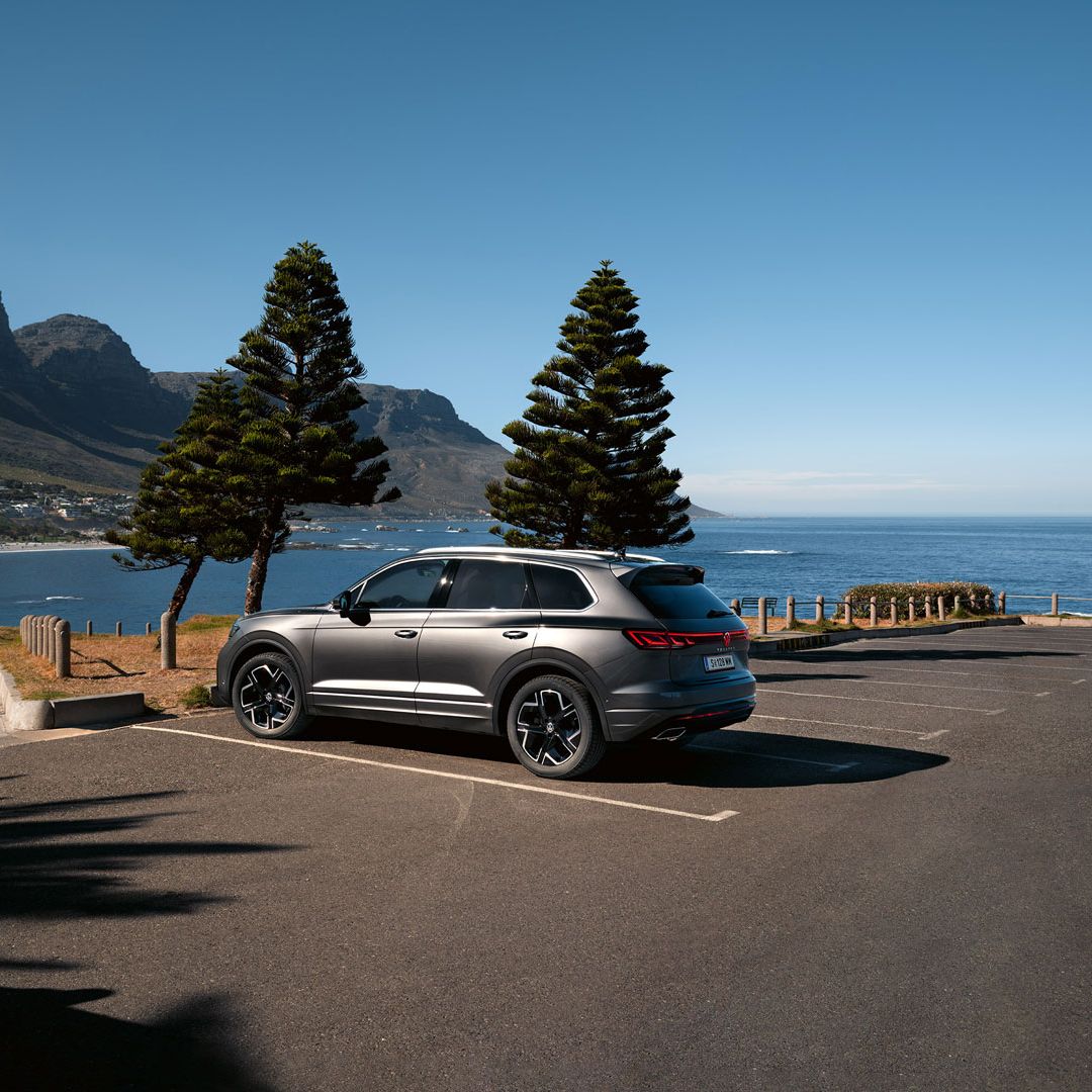 Паркиран на слънце VW Touareg Elegance, страничен изглед с морето и брега на заден план.