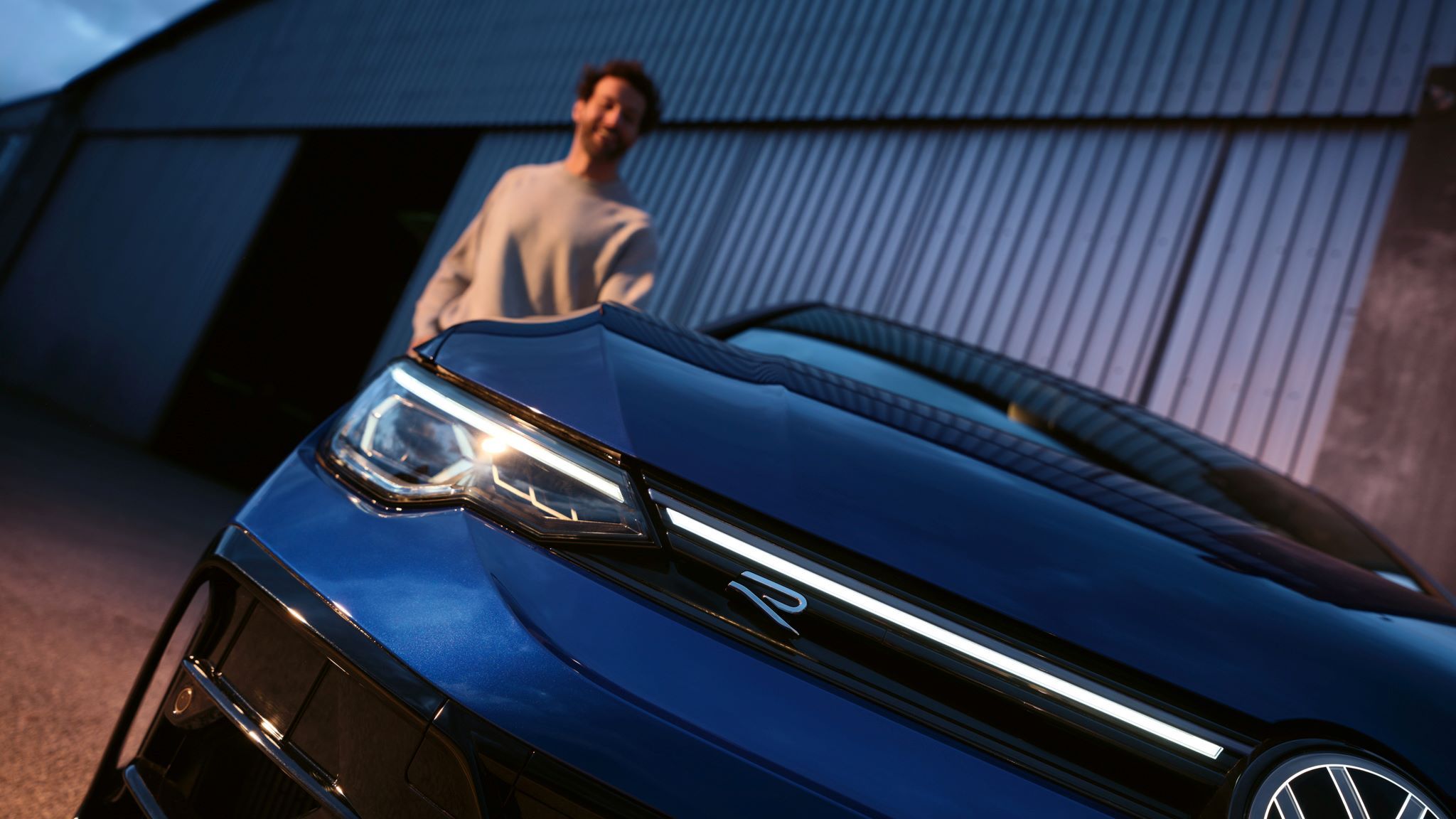 Golf R im Detailshot von der Vorderseite in schräger Ansicht mit Mann im Hintergrund.