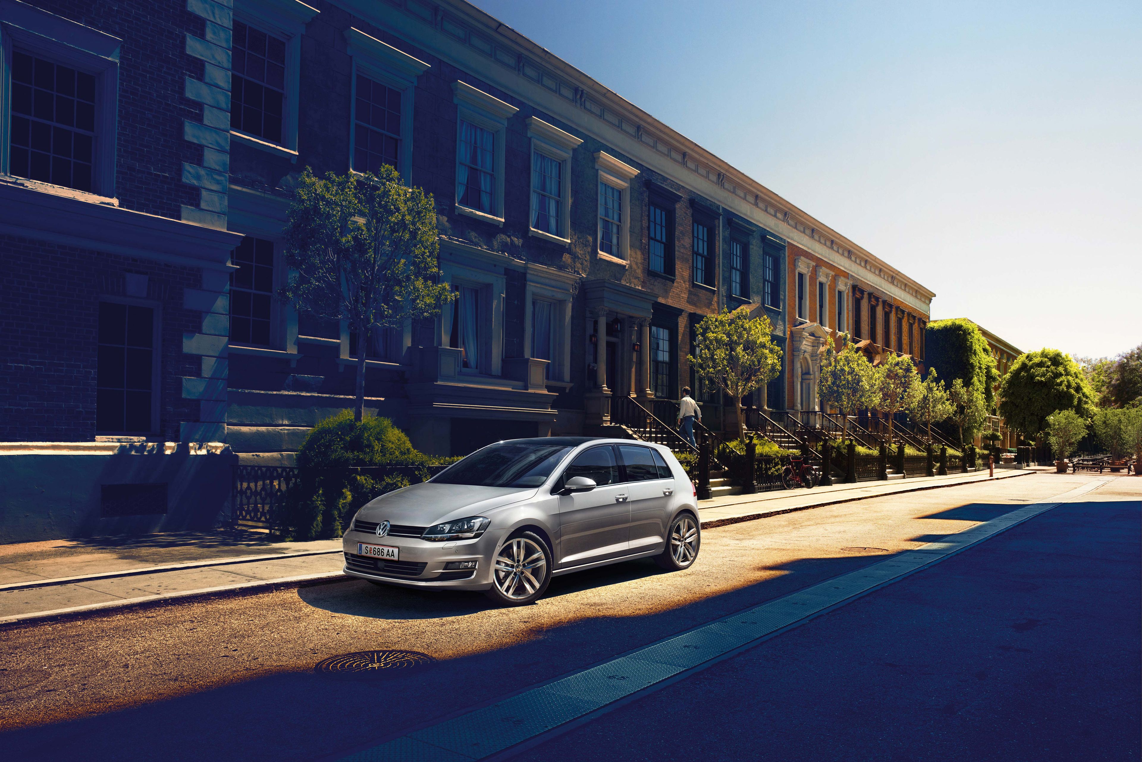 Сребрист Volkswagen Golf, паркиран на улица в слънчев градски район