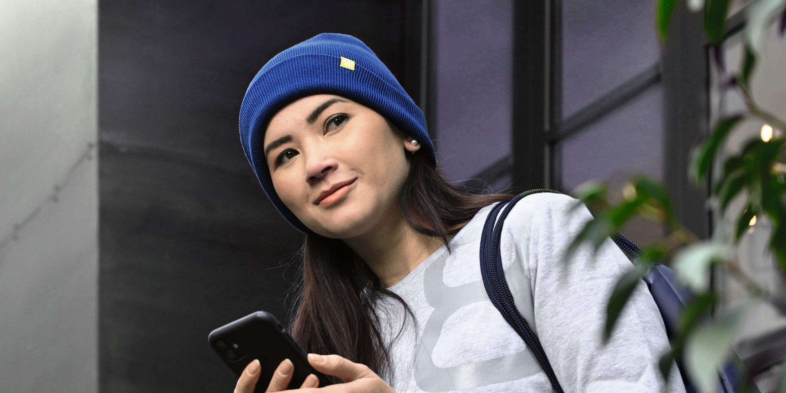 Eine Frau mit Smartphone steht in einem Hauseingang