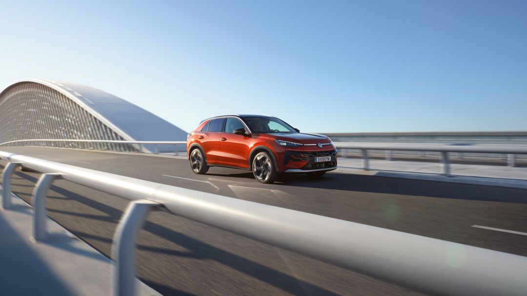 Червен Volkswagen T-Roc в движение по модерен мост.