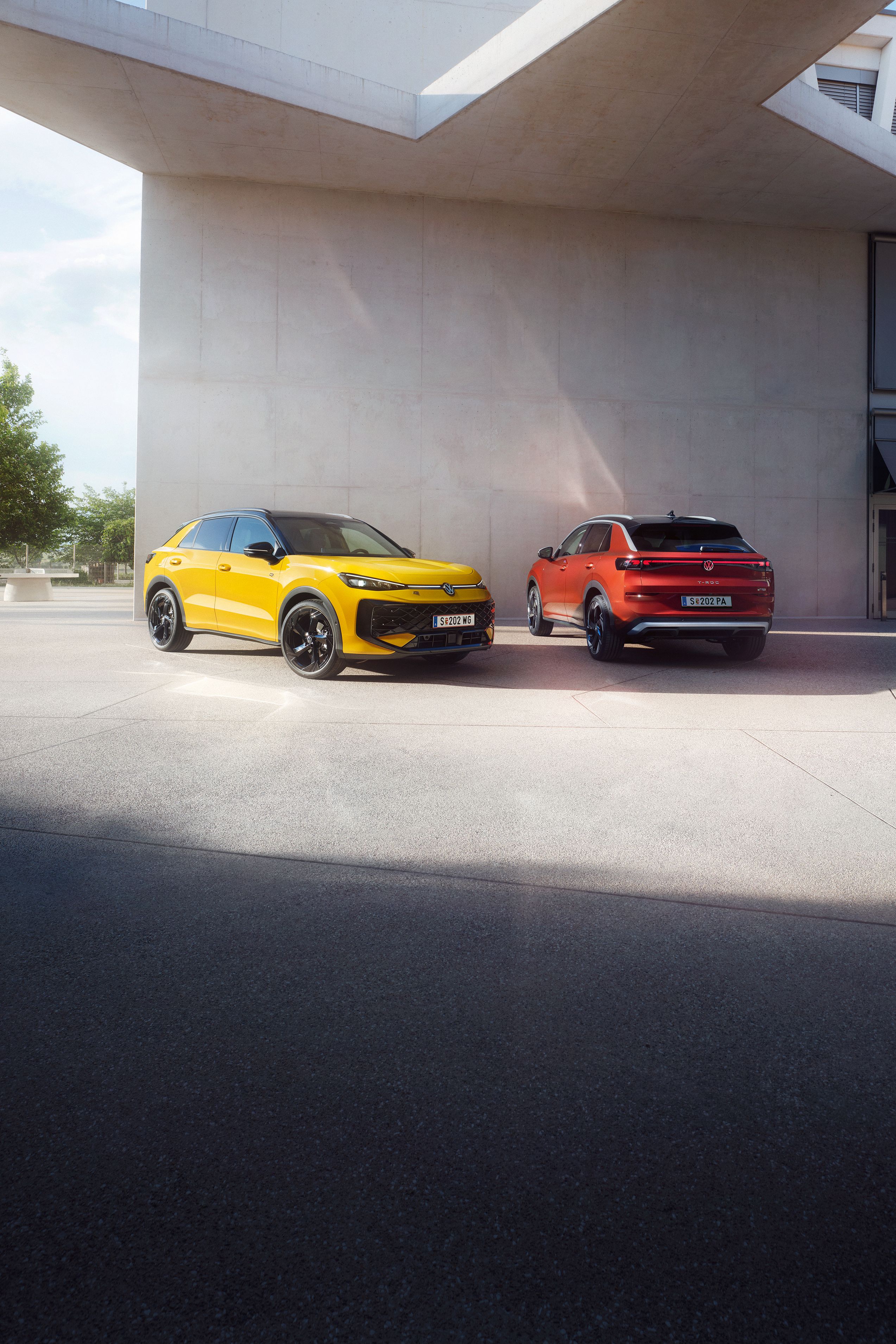 Жълт и червен Volkswagen T-Roc паркирани пред модерна сграда