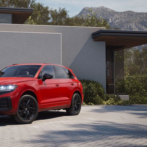 Изглед отпред към страничната част на червен VW Touareg с елементи от R-Line "Exterior Black Style".