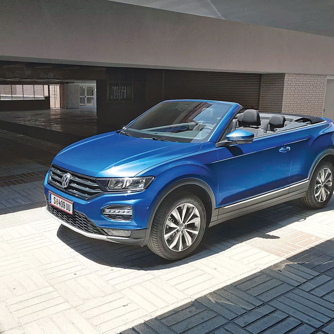 Син Volkswagen T-Roc кабриолет, паркиран под модерен навес с отворен покрив.