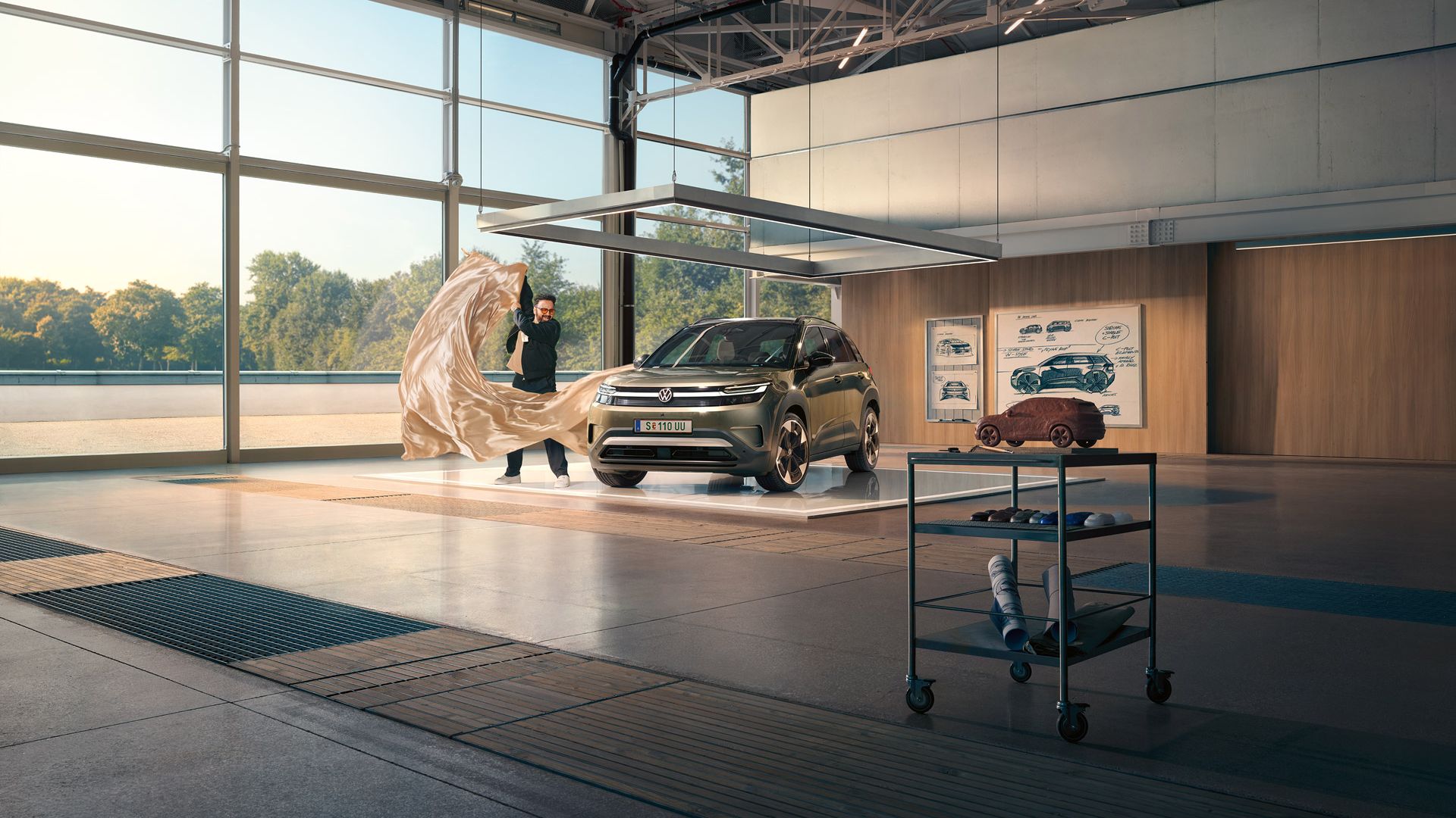 Мъж изважда голяма кърпа от зелен VW ID. Cross, който стои в минималистично дизайнерско студио.