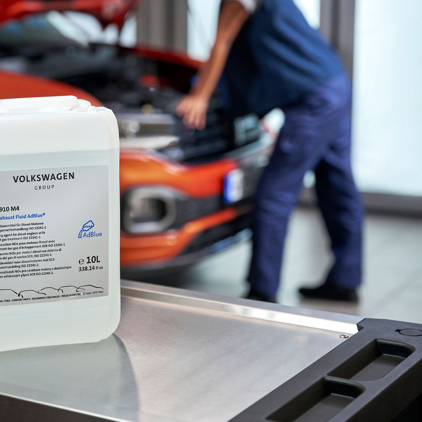 Оригинална течност AdBlue на Volkswagen, поставена на сервизна маса пред автомобил в сервиз.