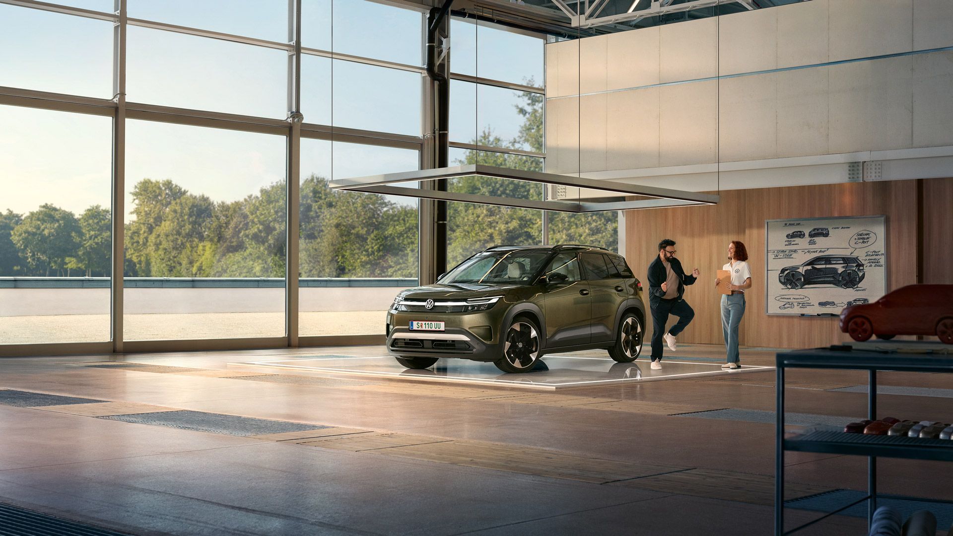 VW ID. Cross е паркиран в минималистично дизайнерско студио, до него развълнуван мъж подскача и разговаря с инженер.