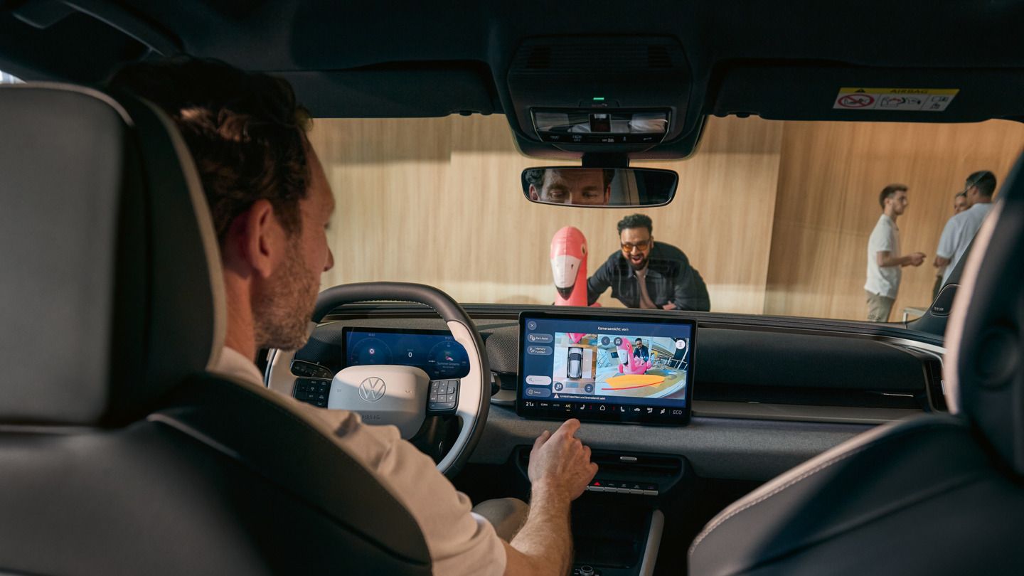 Мъж управлява инфотейнмънт екрана на VW ID. Cross, на екрана се показва изгледът на 360° предната камера.
