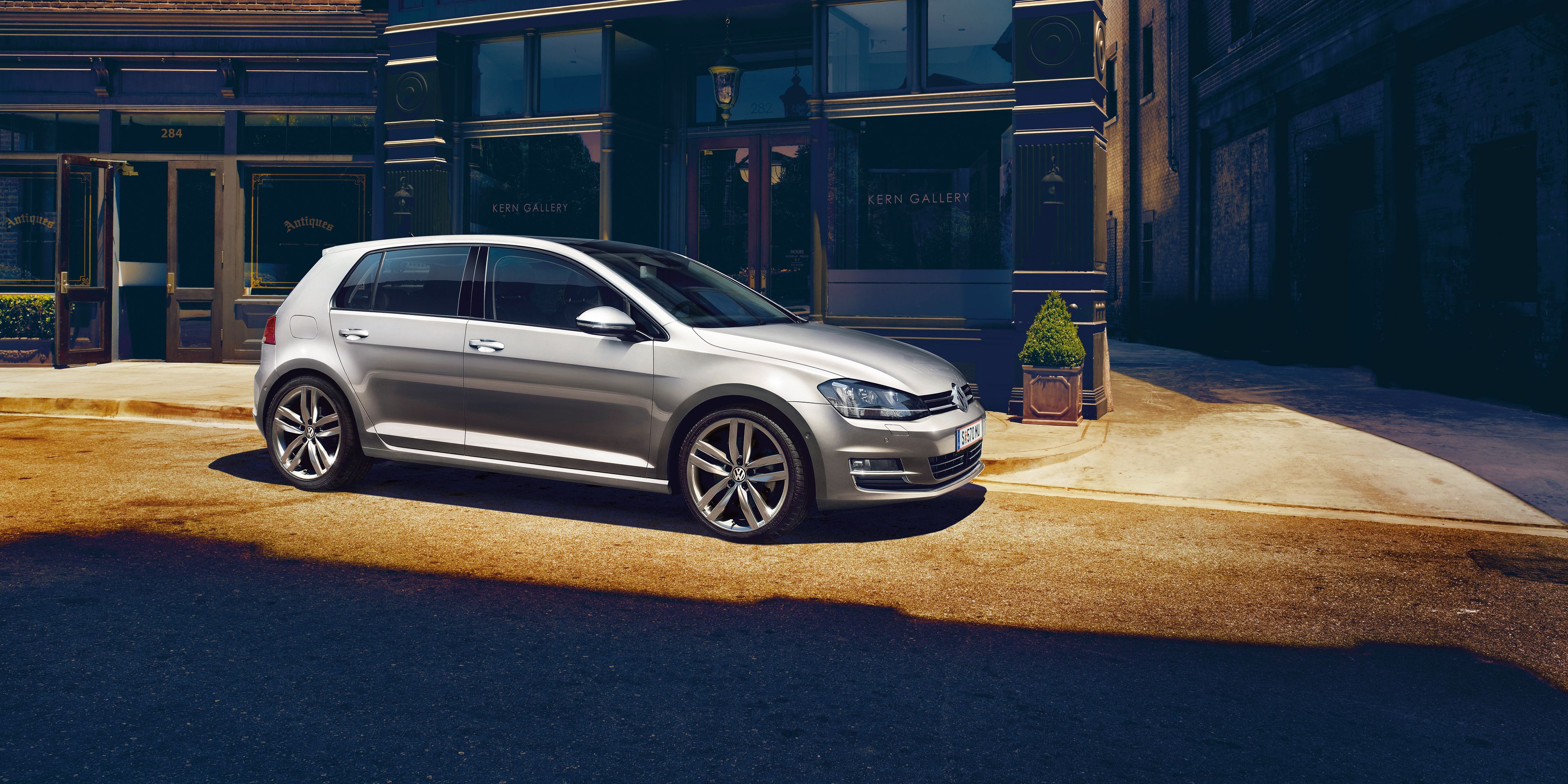 Сребрист Volkswagen Golf, паркиран пред стилна сграда в градска атмосфера