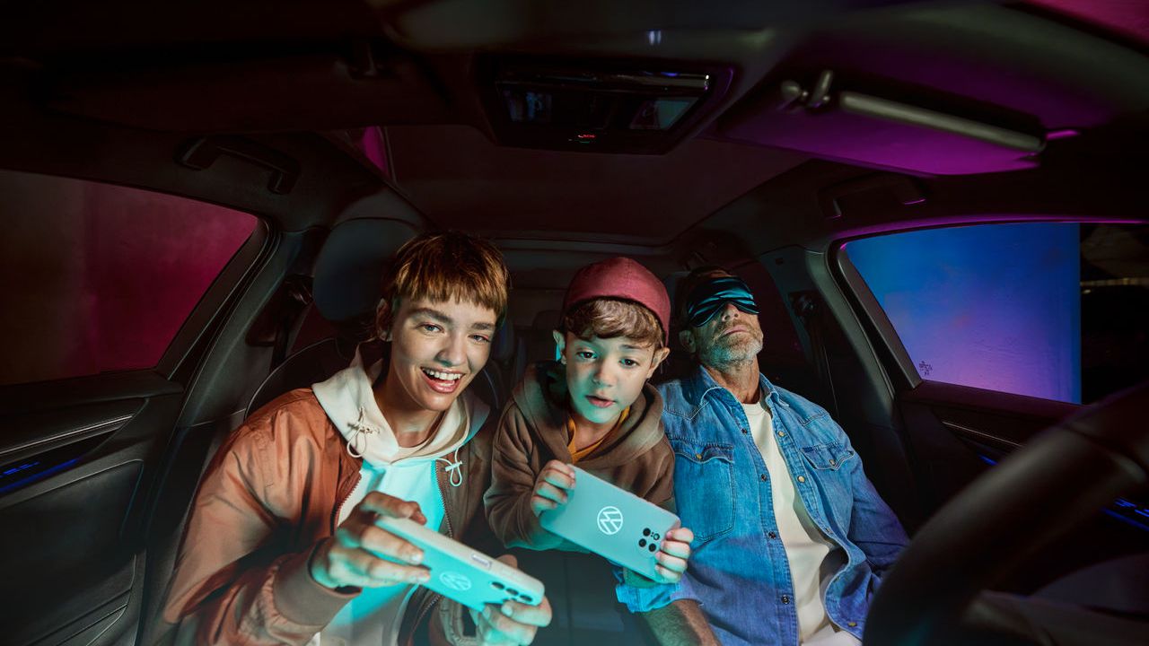 Vater mit zwei Kindern im Volkswagen, die Kinder spielen mit der AirConsole.