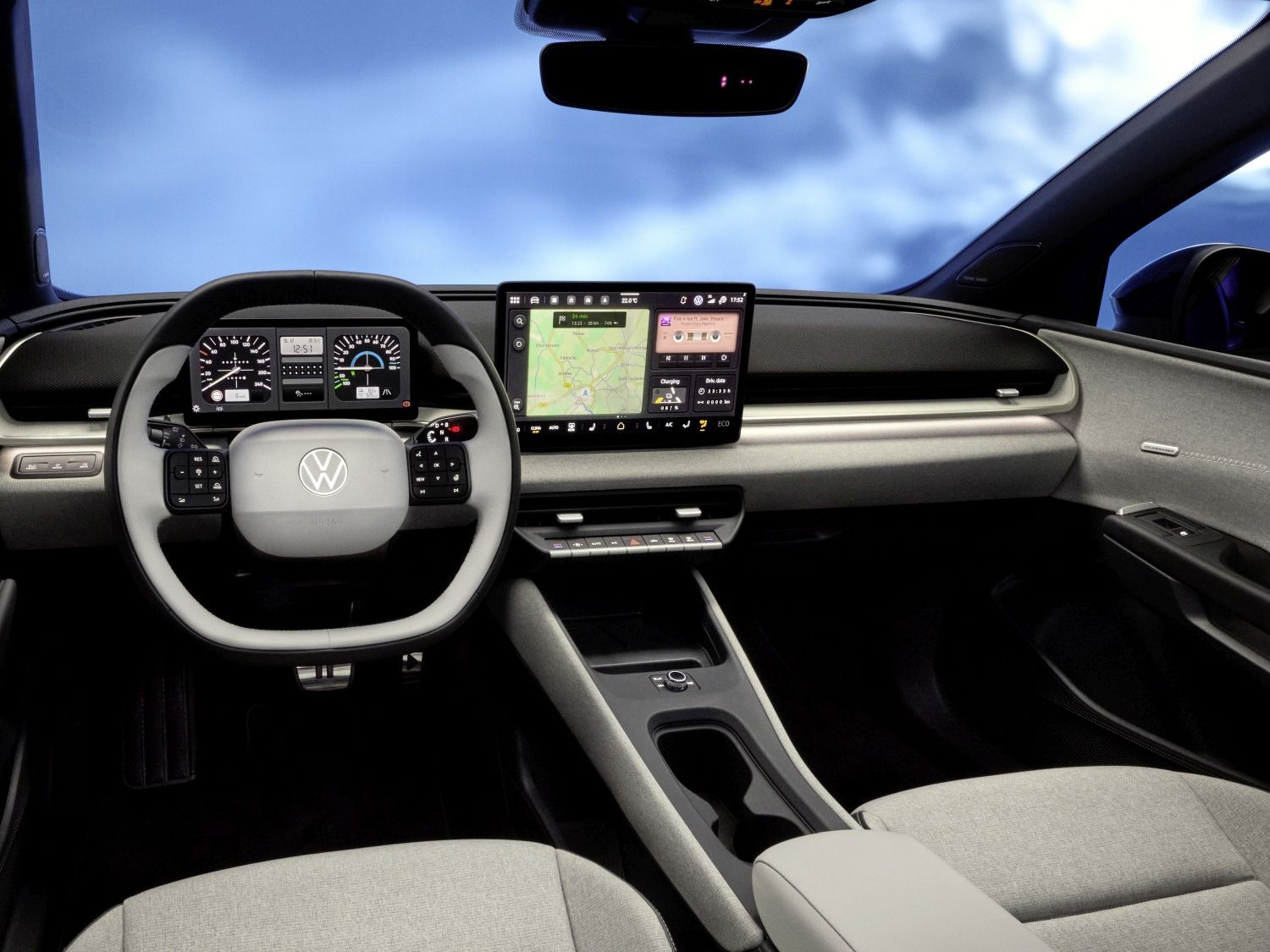 Интериор на модерен автомобил с виртуални панели и голям информационен дисплей. На волана има контролни бутони, а централната конзола е оборудвана с голям сензорен екран, показващ навигационна карта. Вижда се светъл кожен салон и панорамен покрив с изглед към небето.