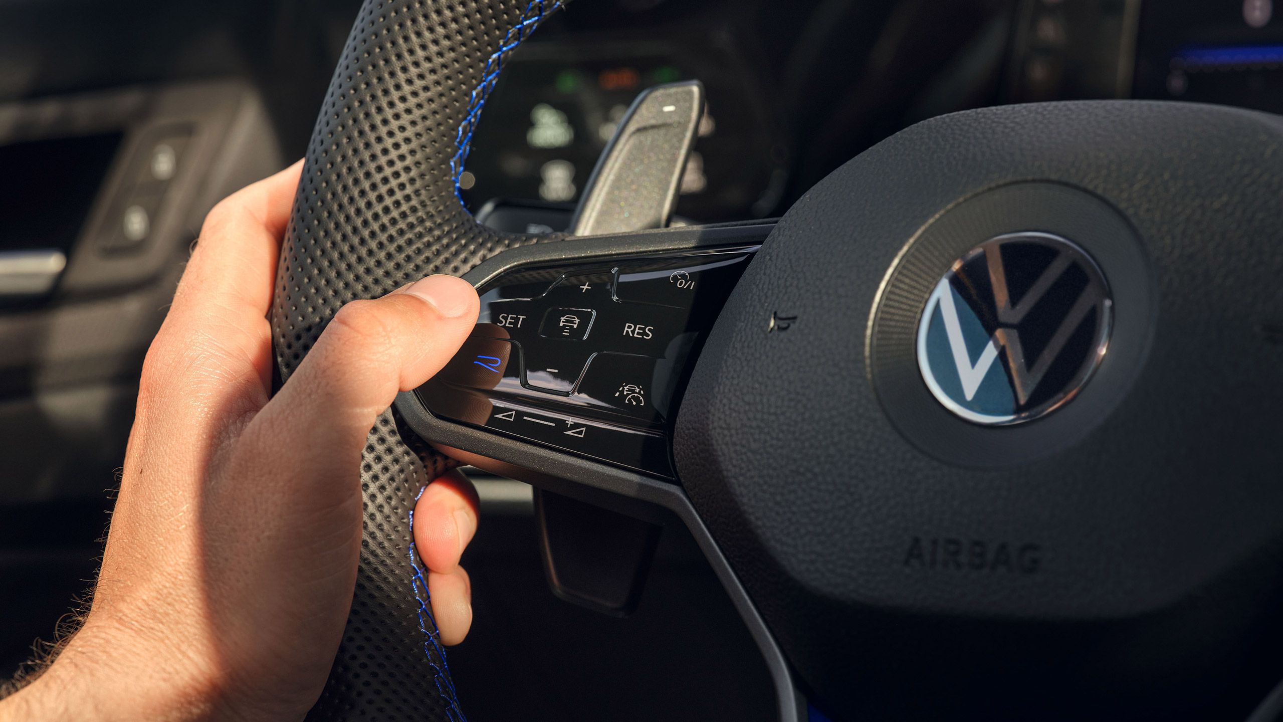 Близък план на волан с лога Volkswagen и управление на асистиращи системи