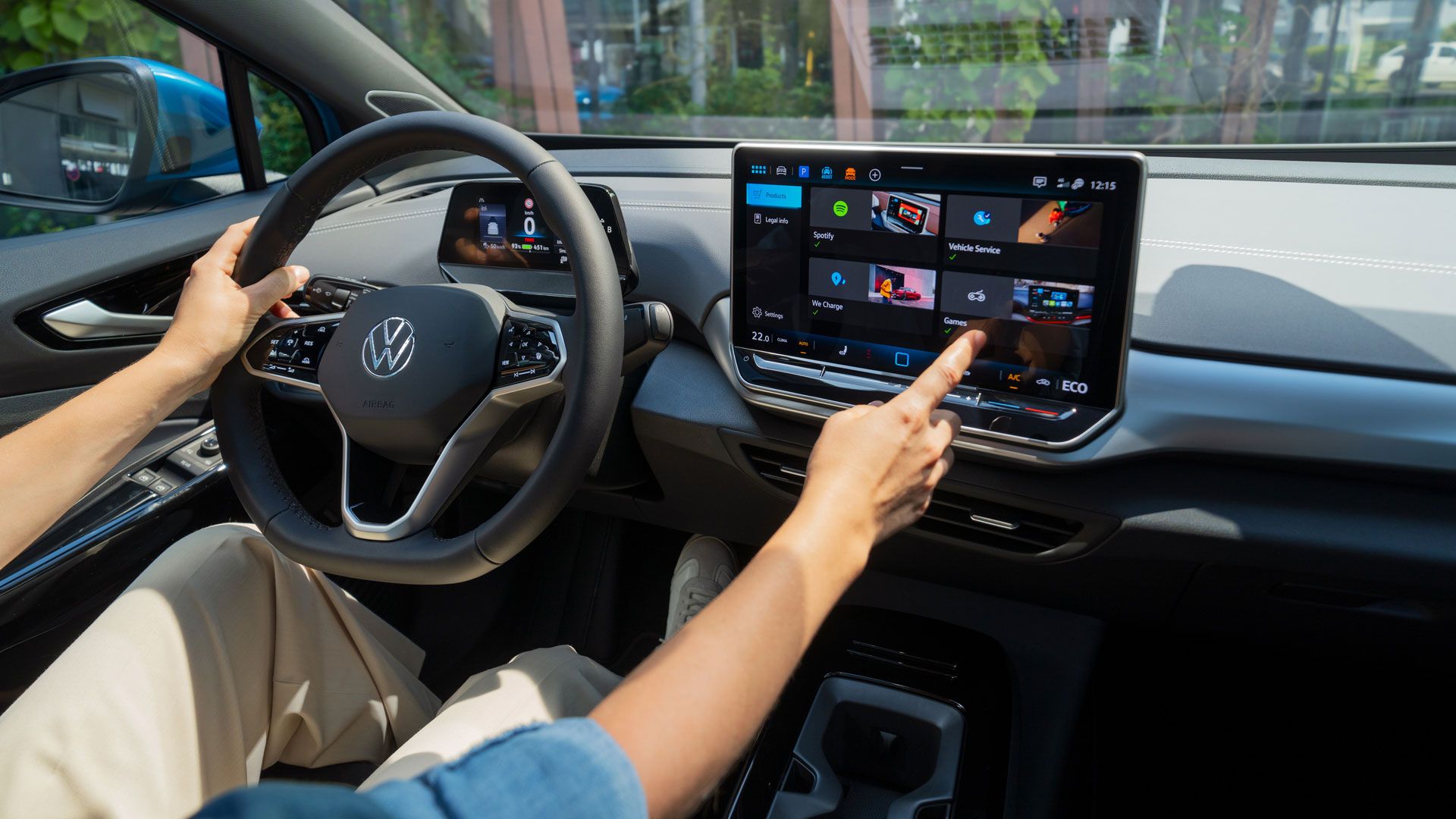 Ansicht vom Interior des ID.4 Pro mit Person welche eine Hand am Lenkrad und die andere am Infotainmentsystem hat.