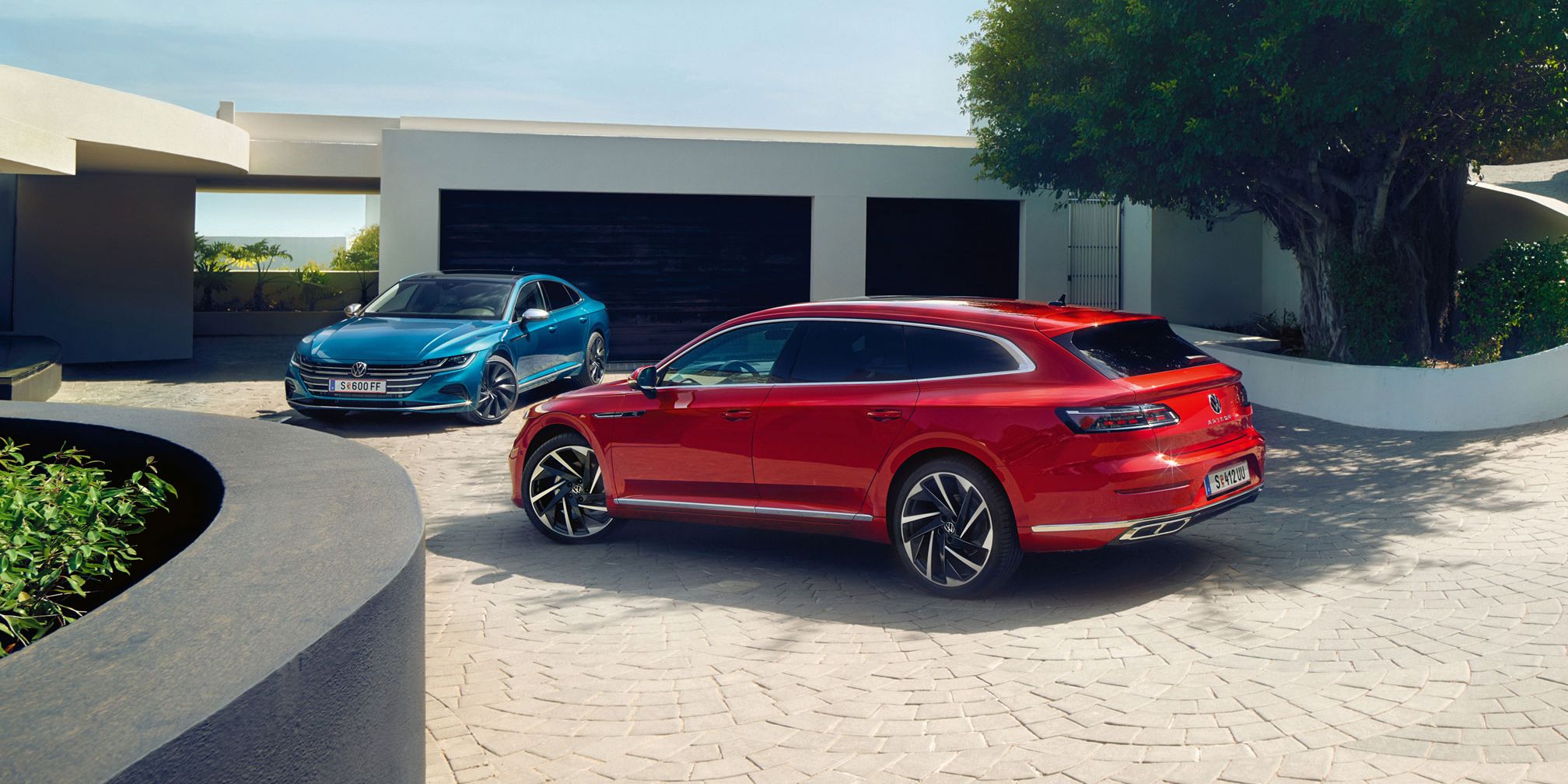 Червен и син Volkswagen Arteon Shooting Brake паркирани пред стилна модерна къща