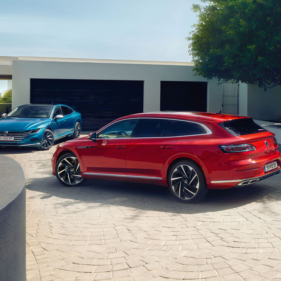 Червен и син Volkswagen Arteon Shooting Brake паркирани пред стилна модерна къща