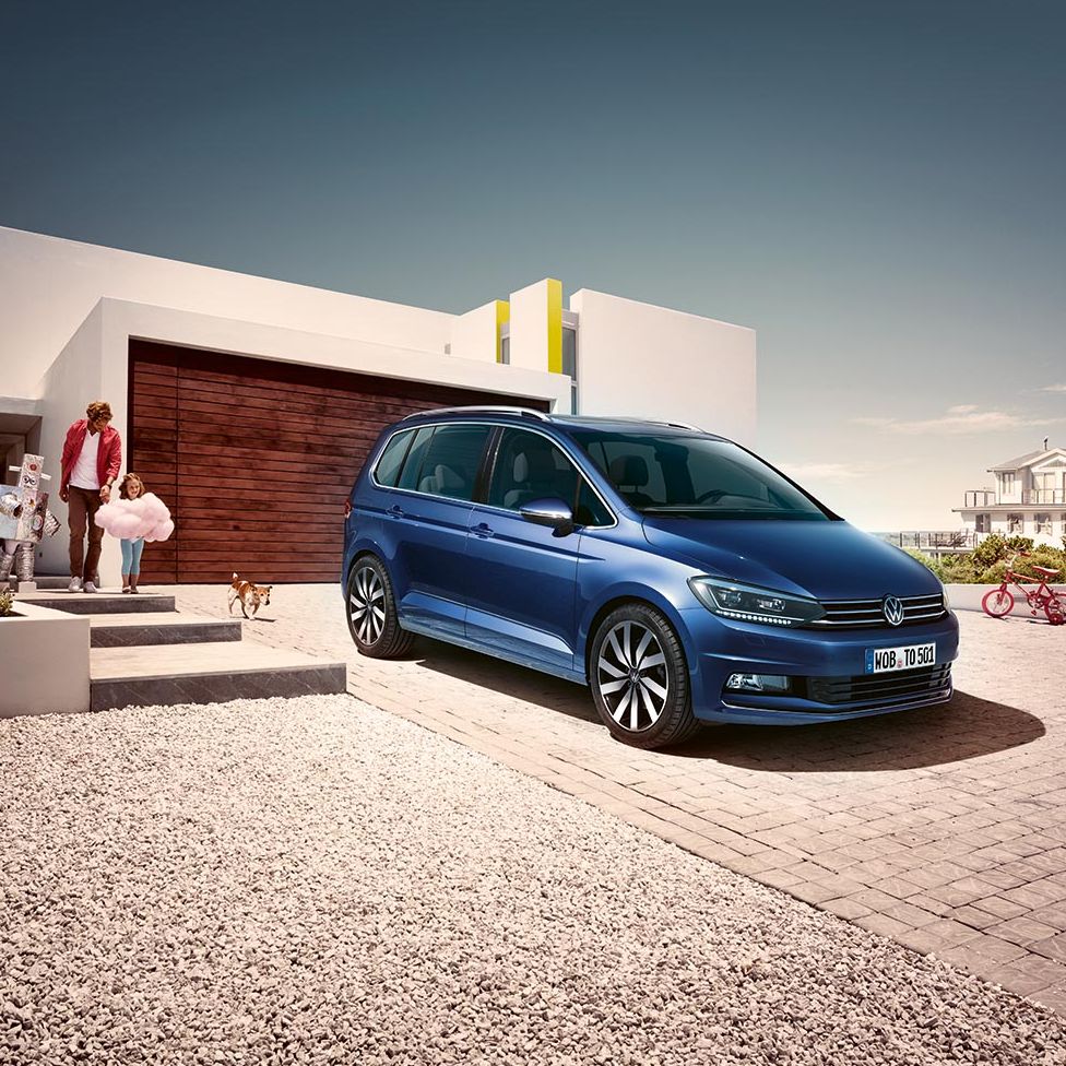 Син Volkswagen Touran паркиран пред модерен дом – перфектен семеен автомобил