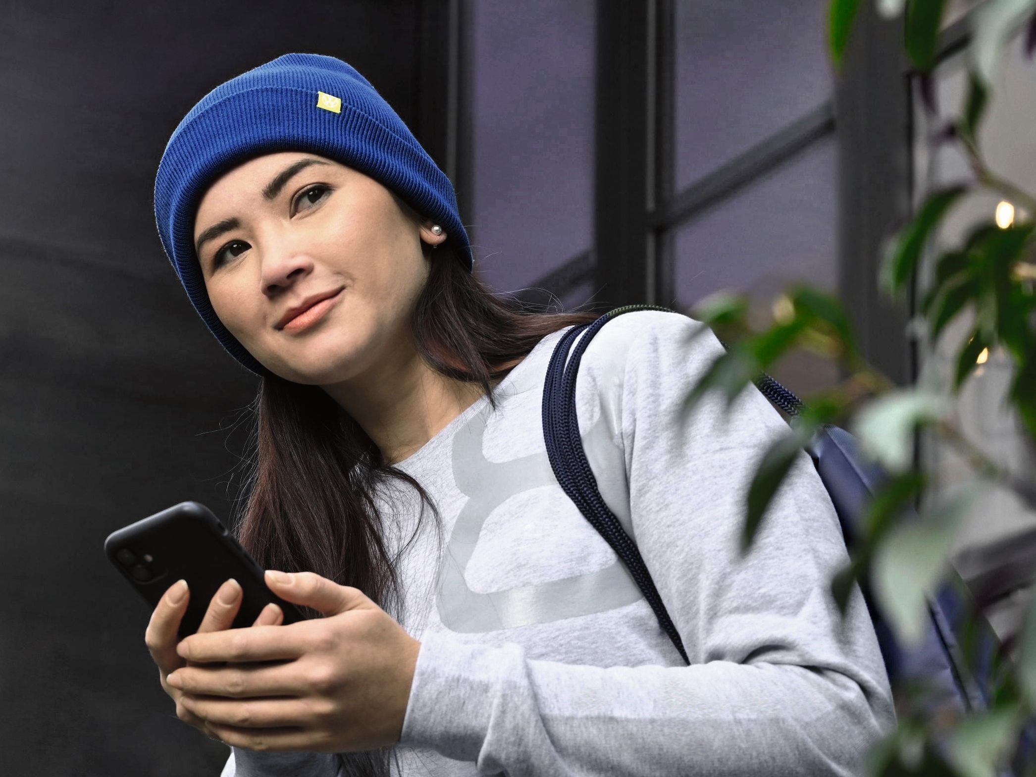 Eine Frau mit Smartphone steht in einem Hauseingang
