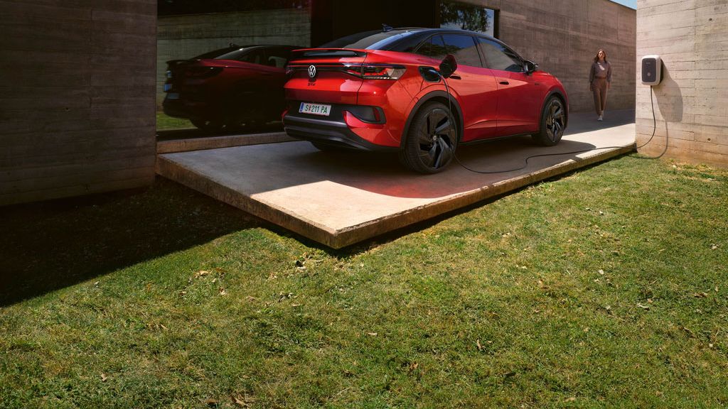 VW ID.5 GTX в червено стои пред модерна сграда и се зарежда на ID. Charger