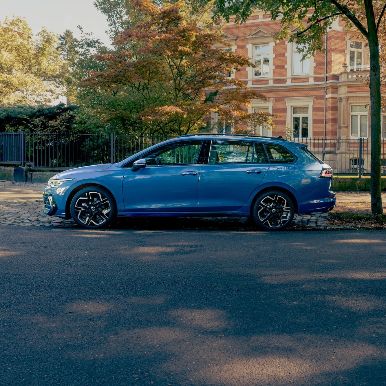 Син Volkswagen Golf Variant, паркиран на тиха улица пред елегантна сграда