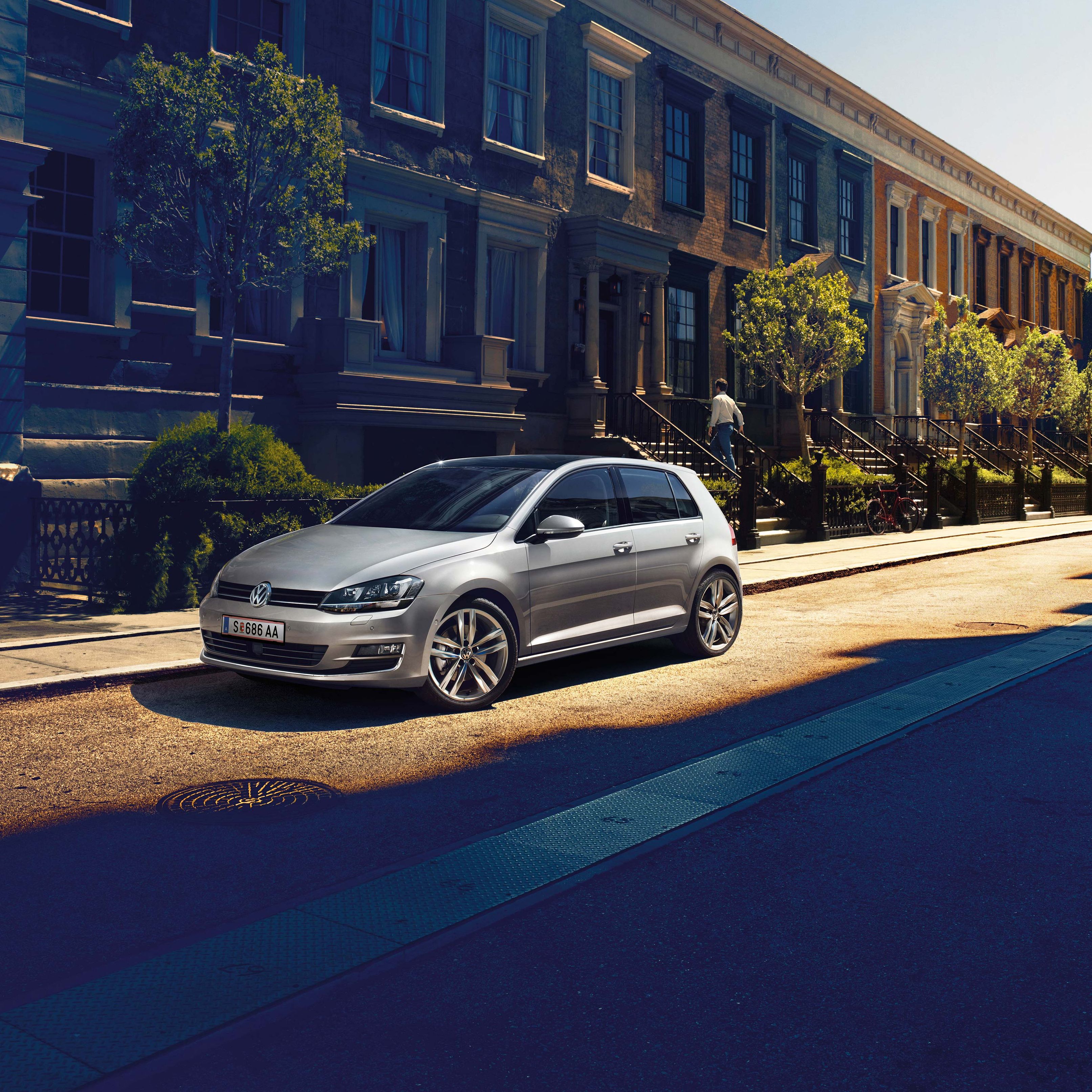 Сребрист Volkswagen Golf, паркиран на улица в слънчев градски район