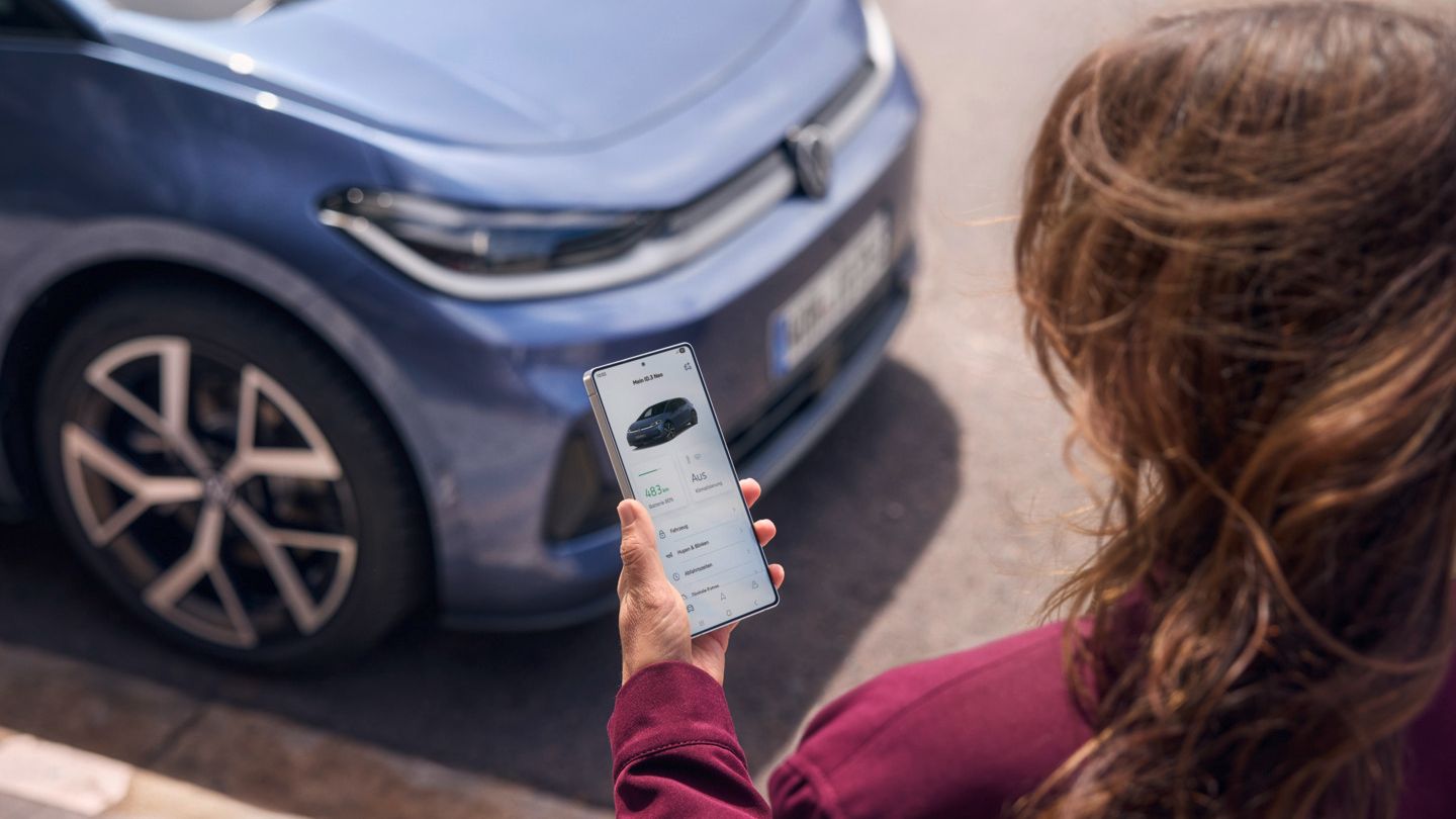Жена гледа смартфона си, пред нея е паркиран син VW ID.3 Neo