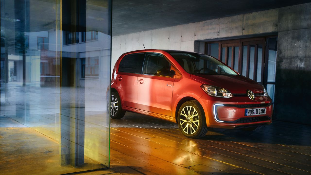 Червен Volkswagen e-up! паркиран в модерна градска сграда с ефектно осветление