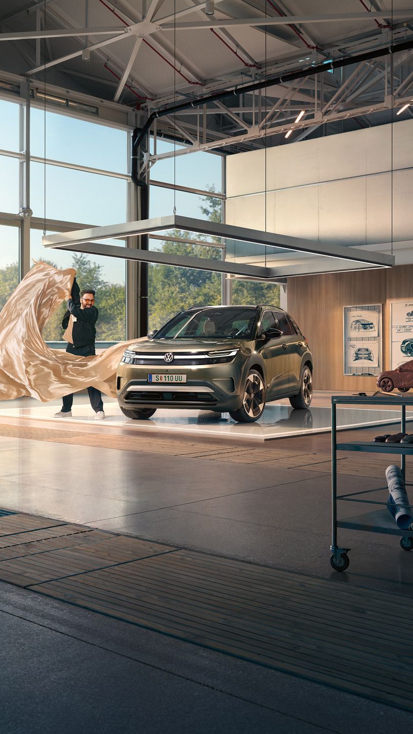 Мъж изважда голяма кърпа от зелен VW ID. Cross, който стои в минималистично дизайнерско студио.