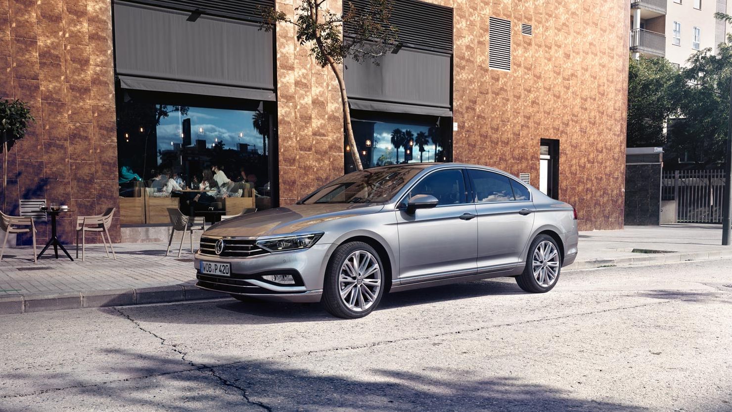 Сребрист Volkswagen Passat паркиран пред кафене в градска среда