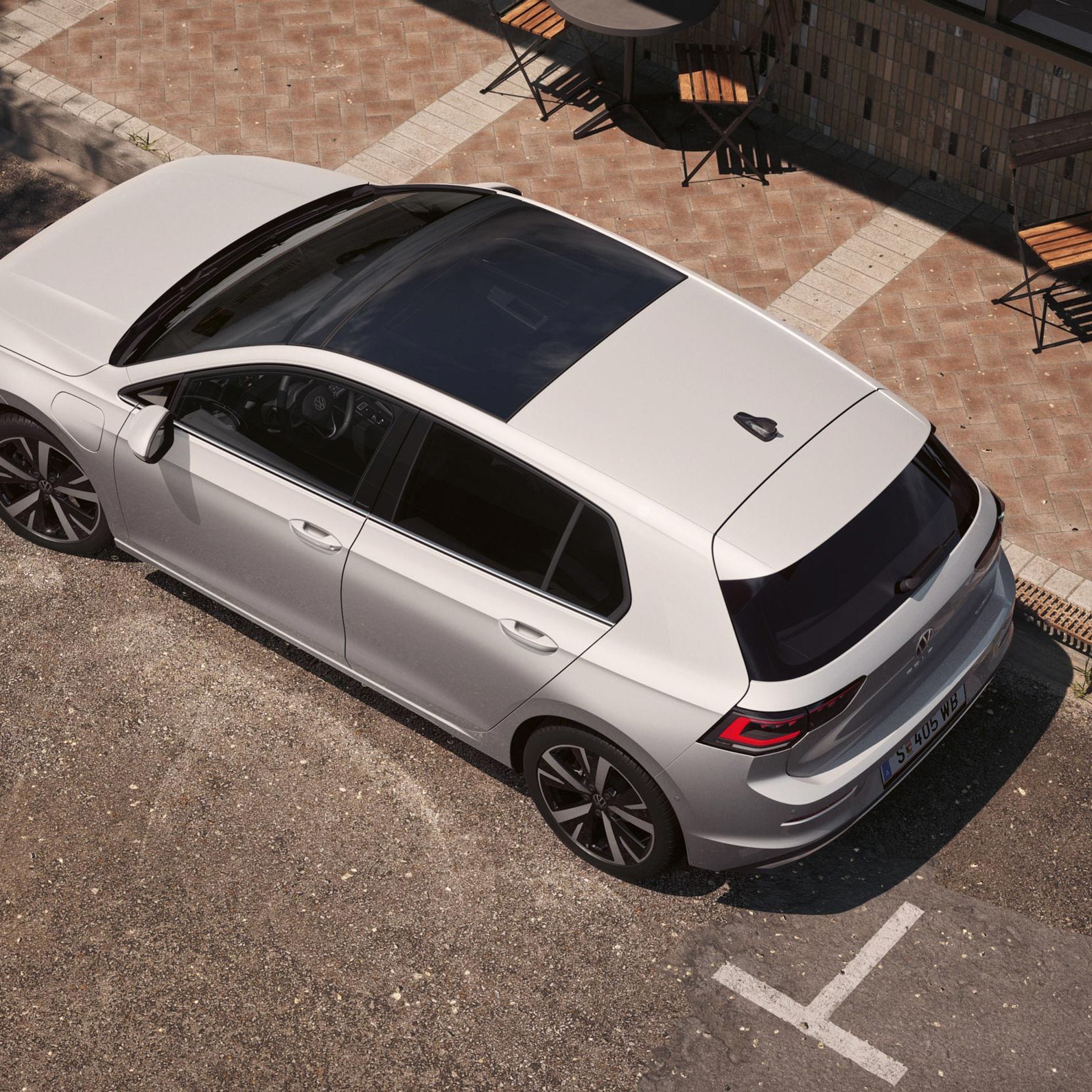 Topview auf einen weißen VW Golf mit Fokus auf das Panoramadach-Aufstell-/Schiebedach. 