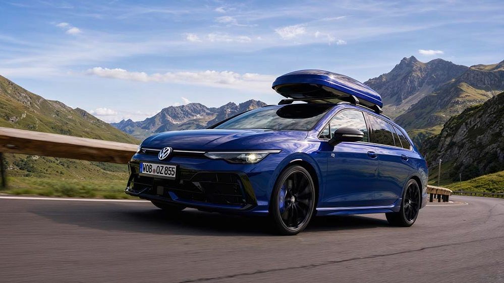Син Golf R с поставена кутия за багаж преминава през планински път