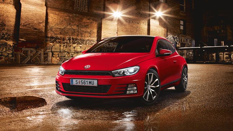 Червено спортно купе Volkswagen, паркирано на мокра улица с графити и нощно осветление.