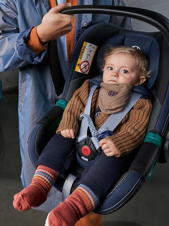 Бебе в столче за кола Volkswagen, носено от родител до паркиран електромобил ID.3.