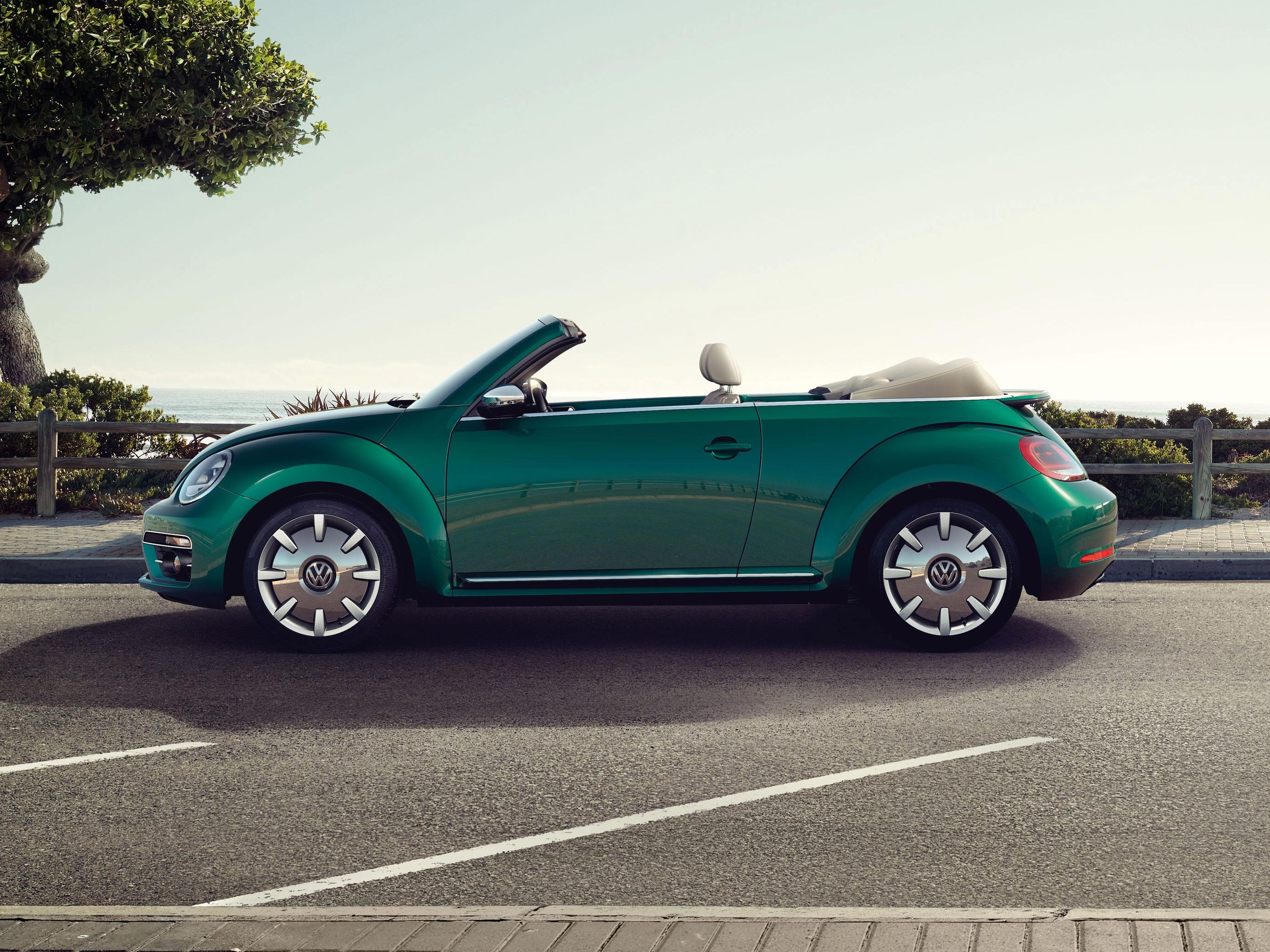 Стилен зелен Volkswagen Beetle Cabriolet паркиран до крайбрежна улица с изглед към морето