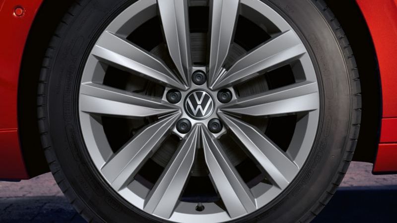 Близък план на алуминиева джанта с емблема Volkswagen на червен Arteon Shooting Brake