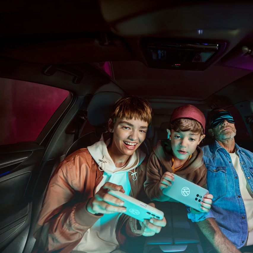 Баща с две деца във Volkswagen, децата играят с AirConsole.